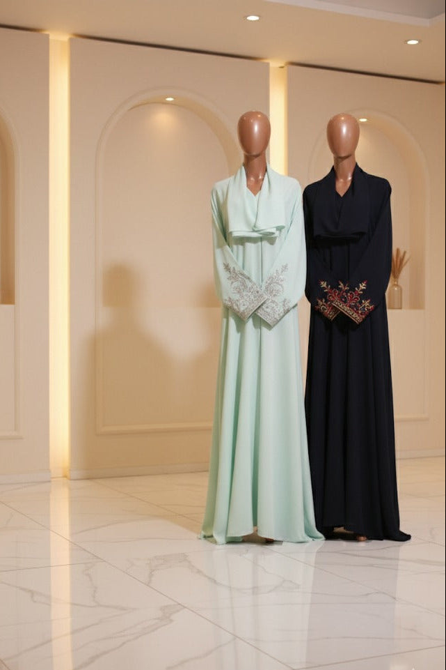 Two mannequins wearing long, elegant dresses in a well-lit indoor setting.