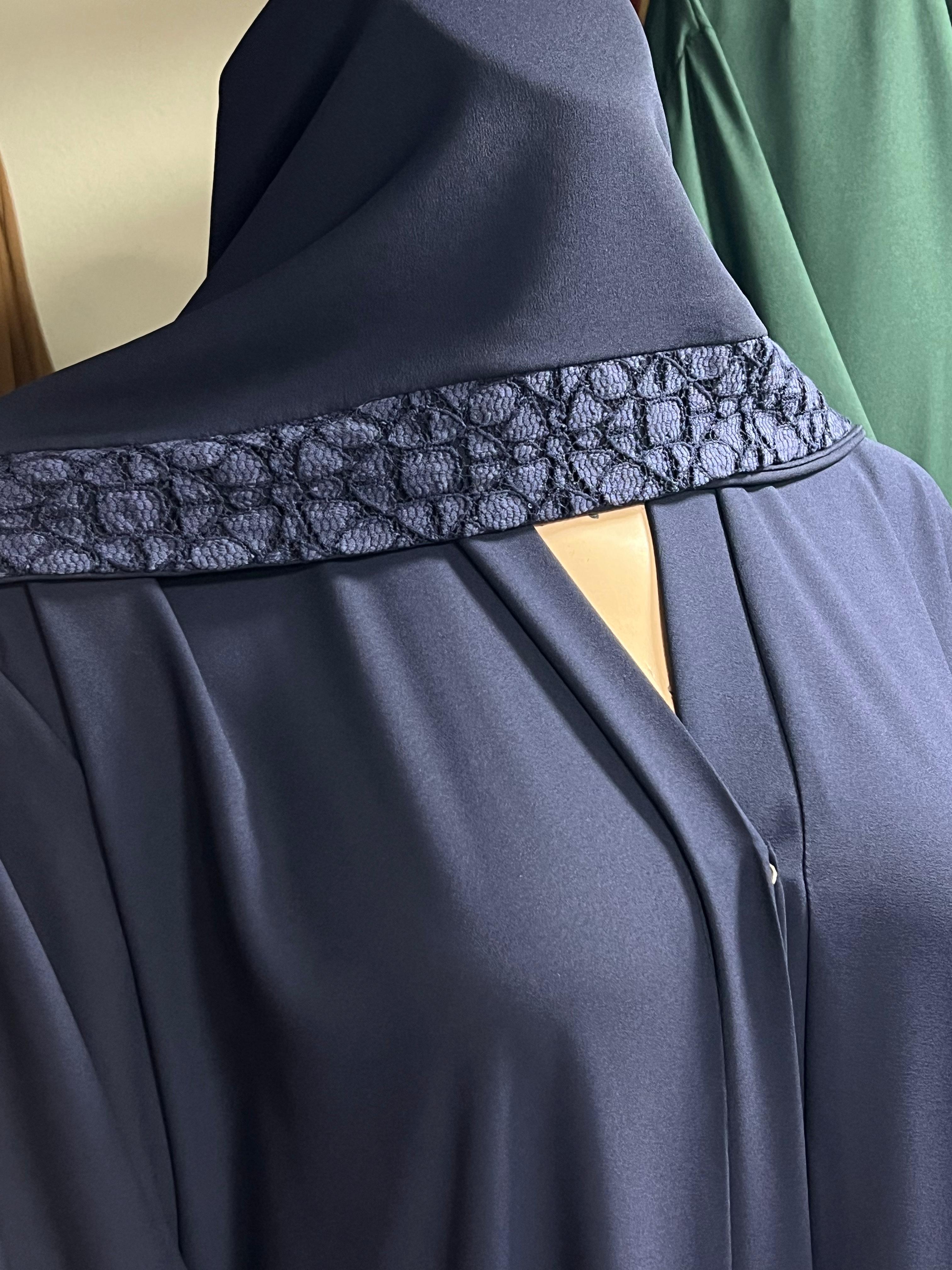 Navy blue abaya with intricate lace detailing on a mannequin against a neutral background